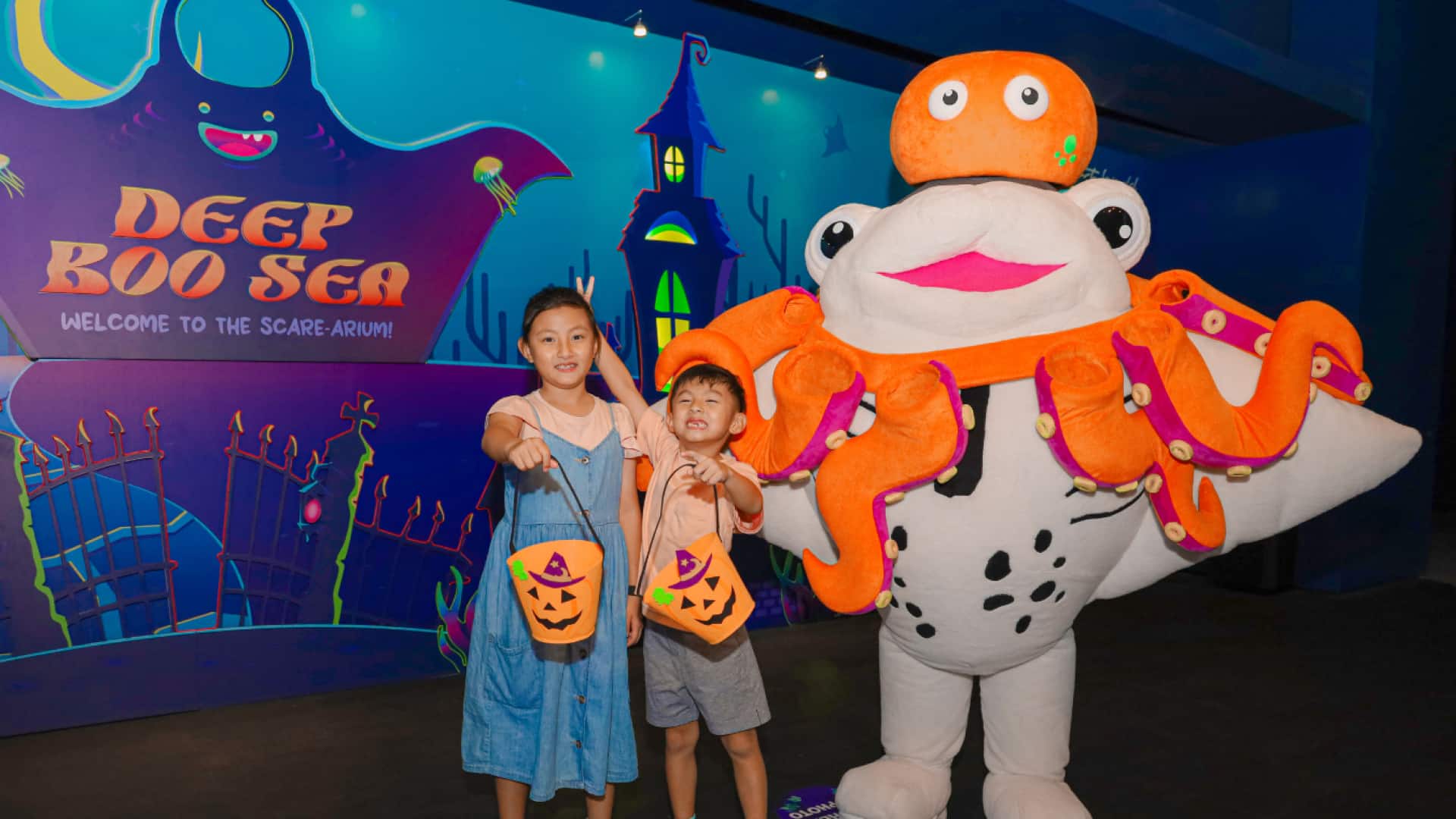 Two children with a manta ray mascot at S.E.A. Aquarium