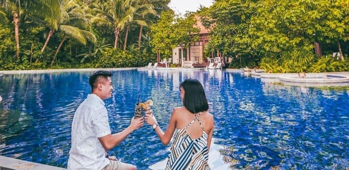 Couple with drinks sitting by the Equarius Villas pool